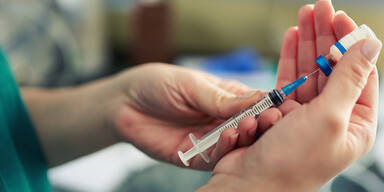 Frau hält Spritze mit Corona-Impfung in den Händen
