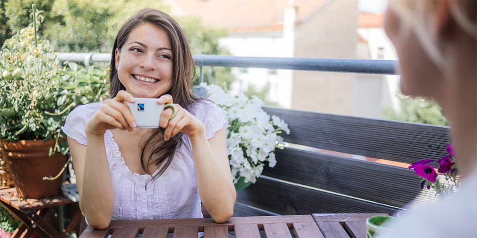 Frau mit Fairtrade-Tasse an Balkontisch