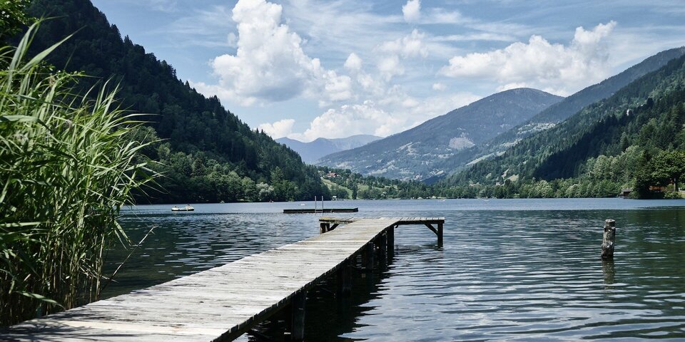 Steg am See umgeben von Bergen und Wäldern